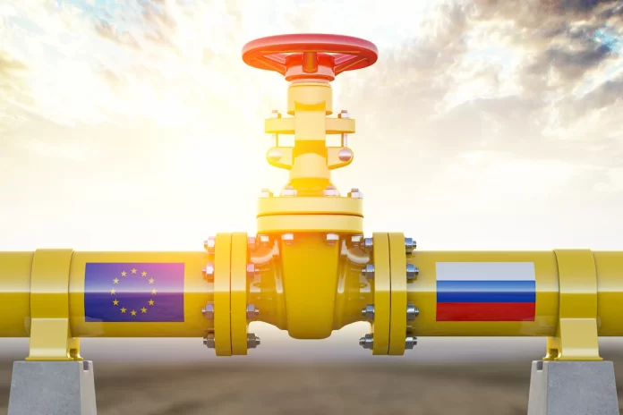 Yellow industrial pipeline valve with flanged joints, EU flag on the left and Russian flag on the right, symbolizing European energy supply.