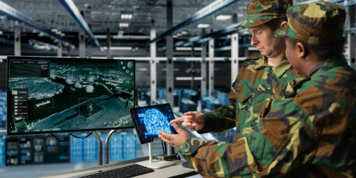 Two soldiers in camouflage analyze a tablet while a large monitor shows a 3D coastal map in a high-tech ops room.