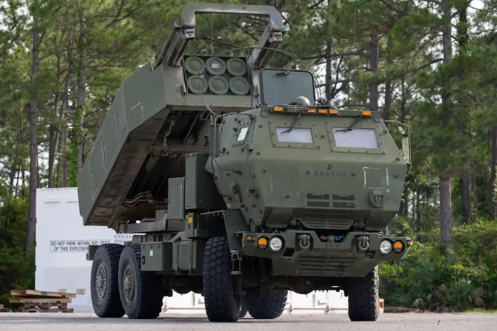Un M142 HIMARS in livrea verde NATO con il modulo di lancio alzato in posizione di fuoco.