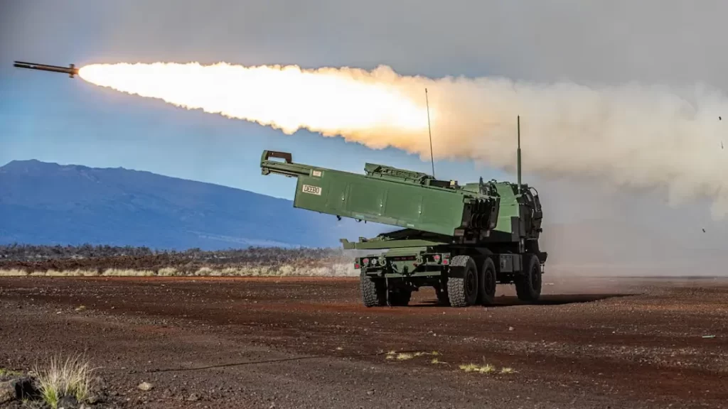Missile launcher firing a long plume of flame across a desert landscape, military vehicle with extended launcher rail elevated.