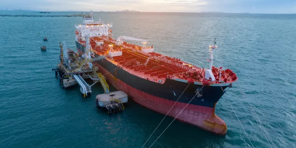grande nave cisterna attraccata a una piattaforma in mare aperto al tramonto
