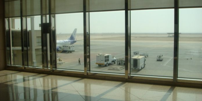 Un aereo di linea parcheggiato sul piazzale dell'aeroporto internazionale King Fahd di Dammam visto dalla sala partenze